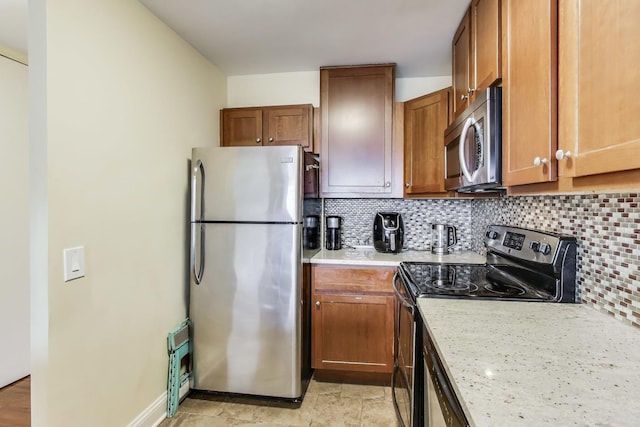 kitchen featuring light stone counters, backsplash, and appliances with stainless steel finishes