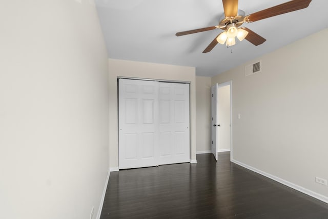 unfurnished bedroom featuring dark hardwood / wood-style flooring, ceiling fan, and a closet