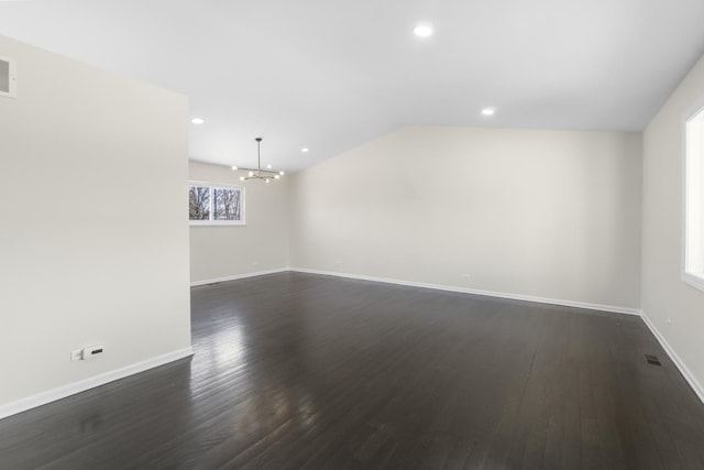 empty room with dark hardwood / wood-style flooring, a notable chandelier, and lofted ceiling