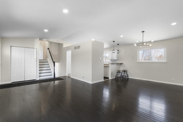 unfurnished living room with lofted ceiling, dark wood-type flooring, and an inviting chandelier