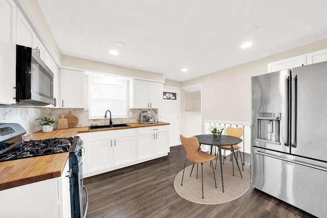 kitchen featuring sink, dark wood-type flooring, wooden counters, appliances with stainless steel finishes, and white cabinetry