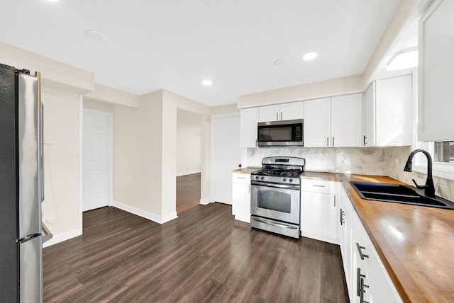 kitchen with sink, backsplash, stainless steel appliances, white cabinets, and wood counters