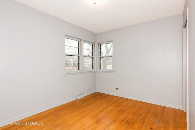 empty room featuring a baseboard radiator and light wood-type flooring