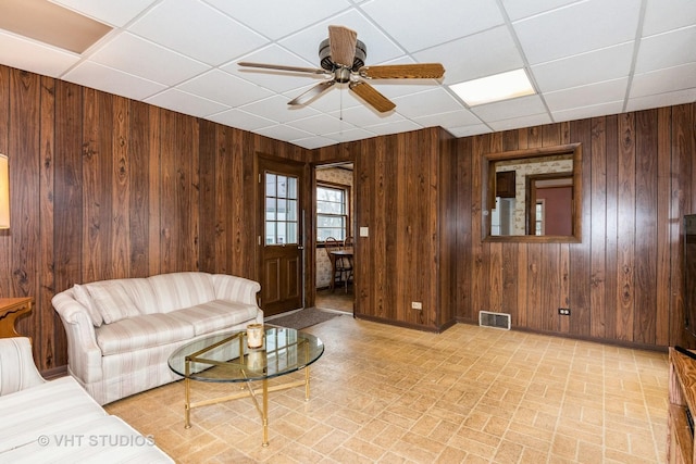 living room featuring a paneled ceiling and wood walls