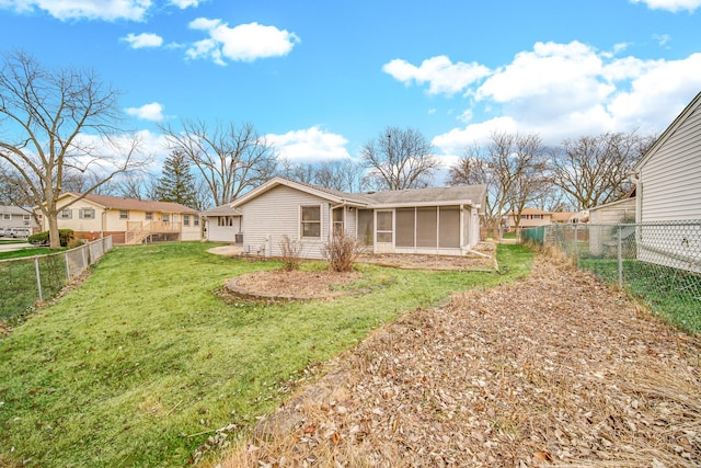 rear view of house featuring a sunroom and a lawn