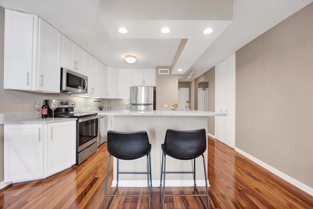 kitchen featuring stainless steel appliances, a center island, hardwood / wood-style floors, and white cabinets