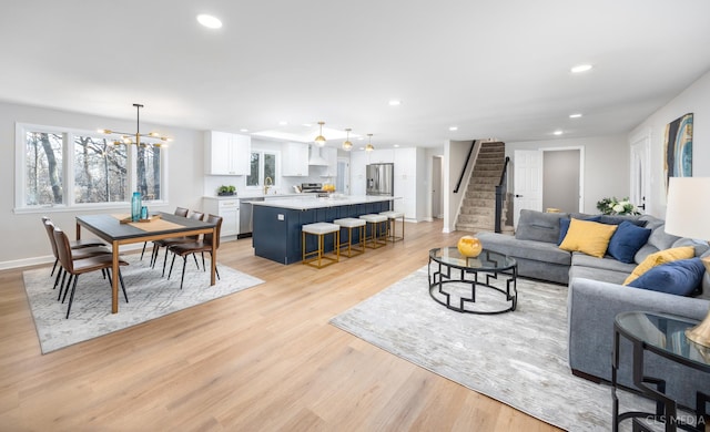 living room featuring sink, light hardwood / wood-style floors, and a notable chandelier