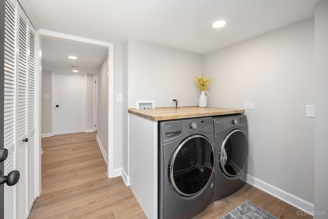 laundry room with washing machine and clothes dryer and light wood-type flooring