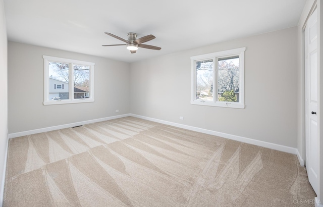 carpeted empty room with ceiling fan and plenty of natural light