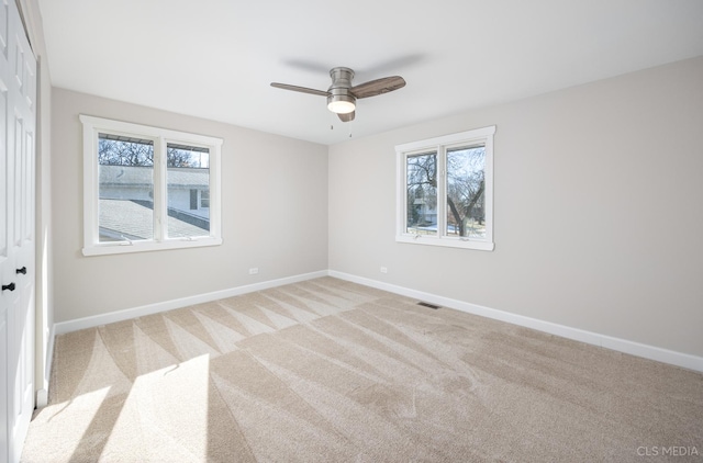 carpeted empty room featuring ceiling fan and a wealth of natural light