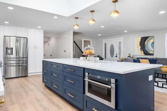 kitchen with blue cabinetry, a center island, pendant lighting, stainless steel appliances, and white cabinets