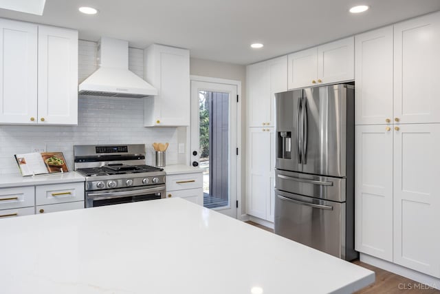 kitchen featuring white cabinets, appliances with stainless steel finishes, and wall chimney range hood