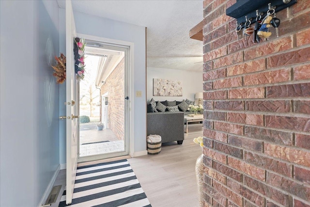 entryway with plenty of natural light, a textured ceiling, and light wood-type flooring