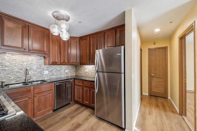 kitchen featuring sink, light hardwood / wood-style flooring, appliances with stainless steel finishes, tasteful backsplash, and decorative light fixtures