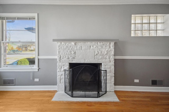 details featuring crown molding, hardwood / wood-style flooring, and a stone fireplace