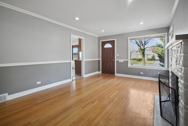 entrance foyer featuring ornamental molding, a fireplace, and light hardwood / wood-style flooring