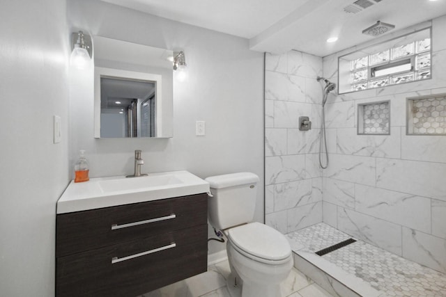 bathroom featuring vanity, toilet, and a tile shower