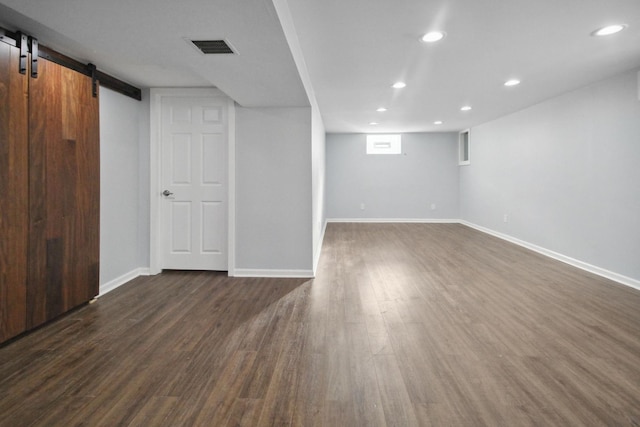 basement featuring dark hardwood / wood-style floors and a barn door