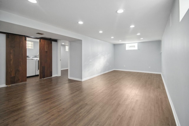 empty room featuring dark hardwood / wood-style floors, washing machine and dryer, and a barn door