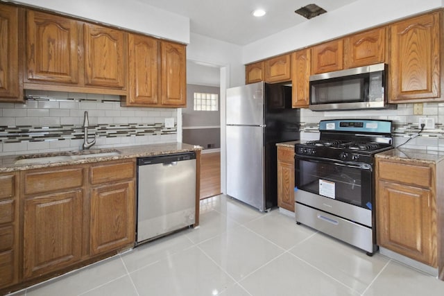 kitchen featuring light stone countertops, light tile patterned flooring, appliances with stainless steel finishes, and sink