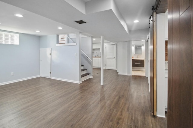 basement with a barn door and dark hardwood / wood-style flooring