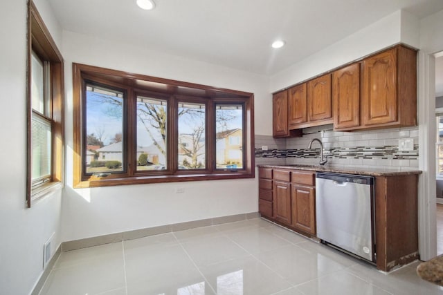 kitchen with light tile patterned flooring, sink, tasteful backsplash, stone countertops, and dishwasher