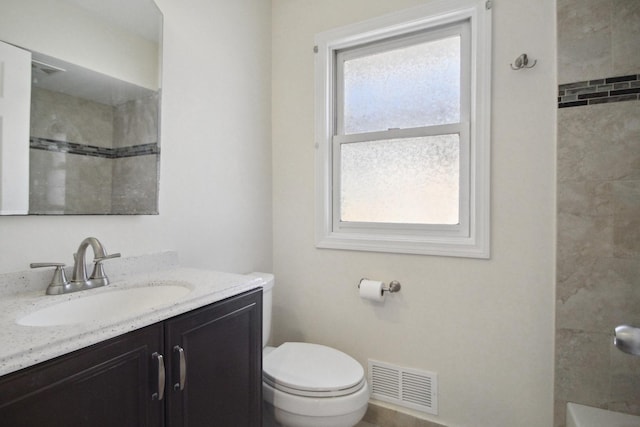 bathroom with vanity, toilet, a wealth of natural light, and a tile shower