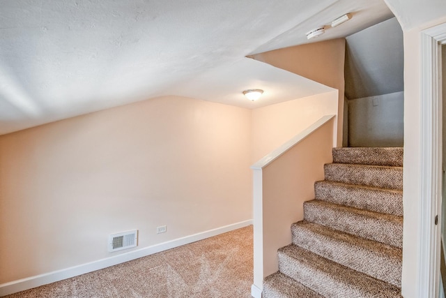 stairway featuring lofted ceiling and carpet