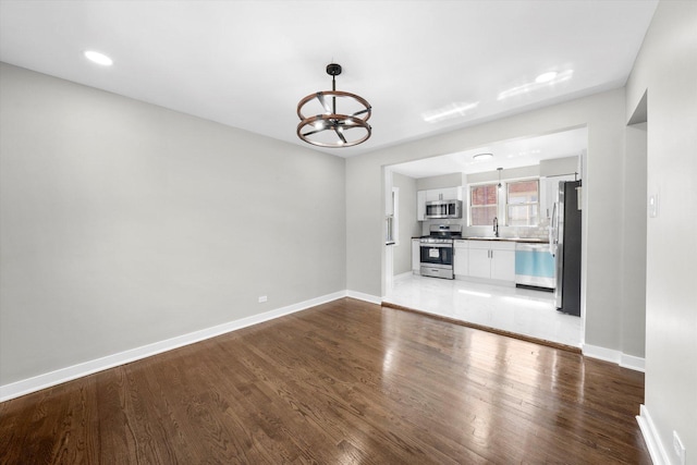 unfurnished living room featuring sink, hardwood / wood-style floors, and an inviting chandelier