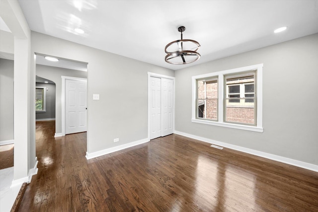 spare room featuring dark wood-type flooring and an inviting chandelier