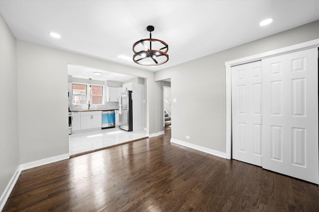 unfurnished living room with dark hardwood / wood-style floors, sink, and a notable chandelier