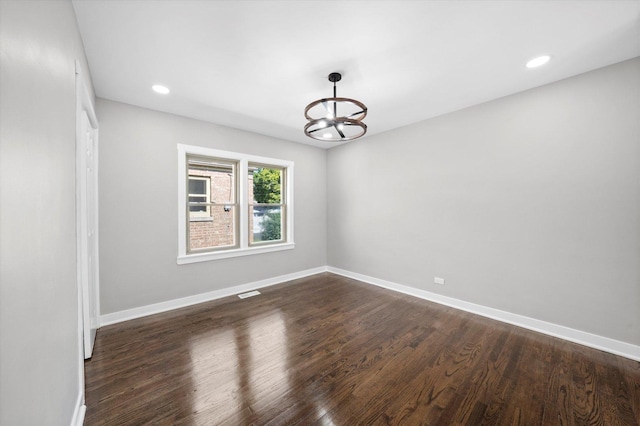 unfurnished room featuring dark hardwood / wood-style flooring and a chandelier