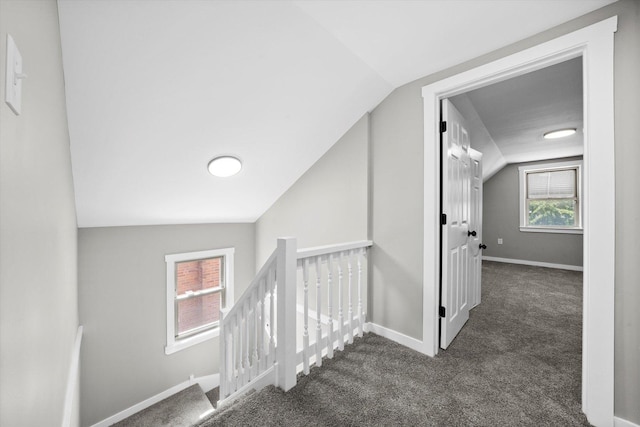 hall with lofted ceiling and dark carpet