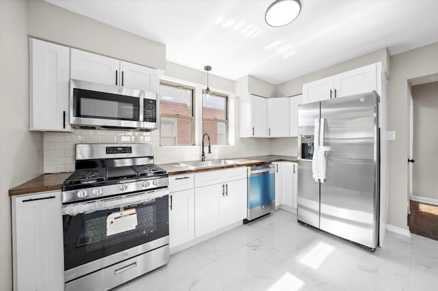 kitchen with tasteful backsplash, white cabinetry, appliances with stainless steel finishes, and sink