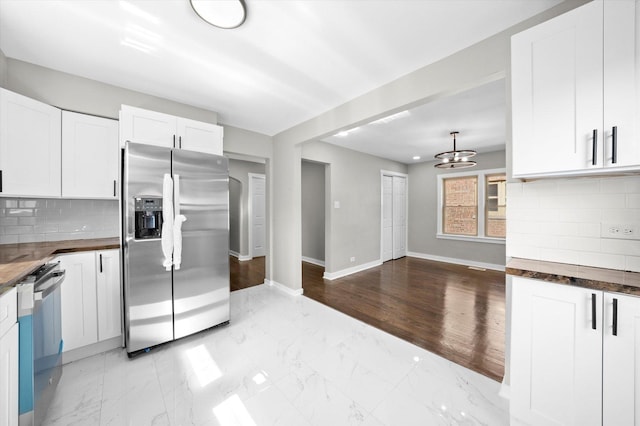 kitchen featuring wooden counters, appliances with stainless steel finishes, a notable chandelier, decorative backsplash, and white cabinets