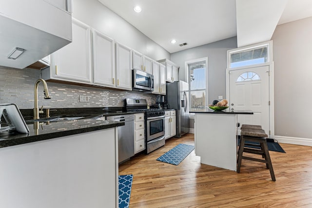 kitchen with sink, appliances with stainless steel finishes, a kitchen breakfast bar, a center island, and white cabinets