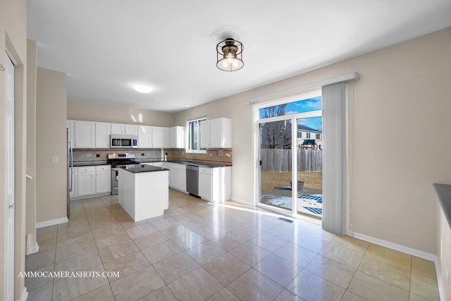 kitchen featuring light tile patterned flooring, appliances with stainless steel finishes, tasteful backsplash, white cabinetry, and a center island