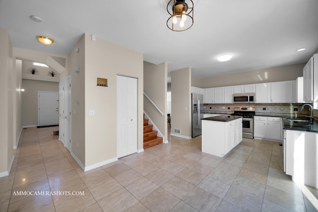 kitchen featuring sink, appliances with stainless steel finishes, white cabinetry, backsplash, and a kitchen island