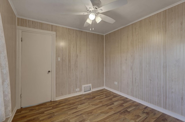 empty room with ceiling fan, wood-type flooring, and ornamental molding