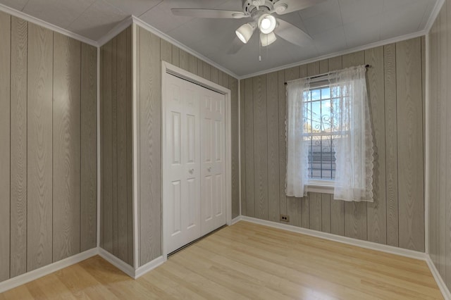 unfurnished bedroom with ornamental molding, light wood-type flooring, ceiling fan, and a closet