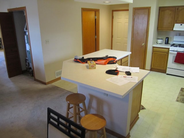 kitchen featuring a breakfast bar area, a kitchen island, white range with gas stovetop, and exhaust hood