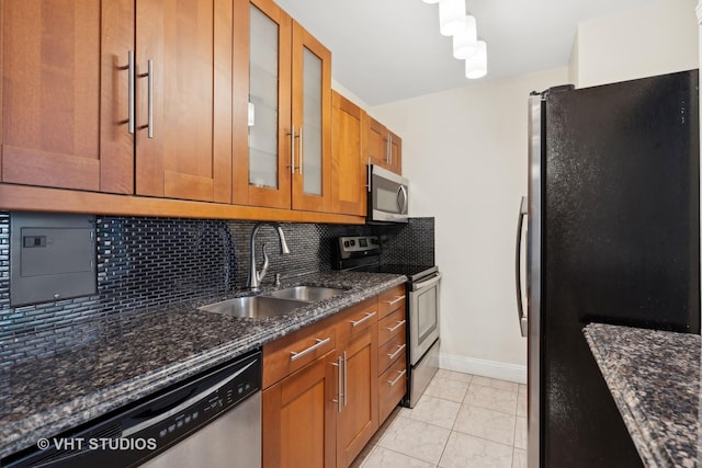 kitchen featuring sink, light tile patterned floors, dark stone countertops, backsplash, and stainless steel appliances