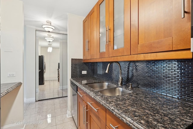 kitchen with light tile patterned flooring, appliances with stainless steel finishes, sink, dark stone countertops, and backsplash