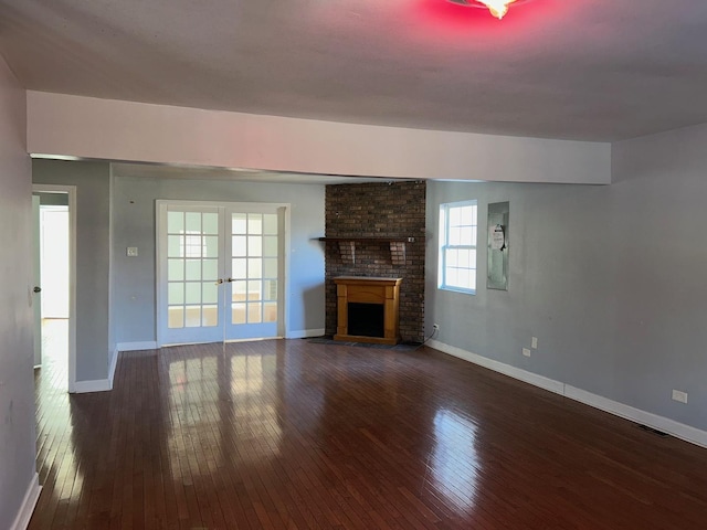 unfurnished living room featuring a brick fireplace, dark hardwood / wood-style floors, and french doors