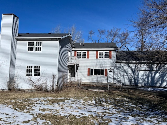 snow covered back of property with a balcony