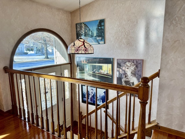 staircase featuring hardwood / wood-style flooring and a textured wall