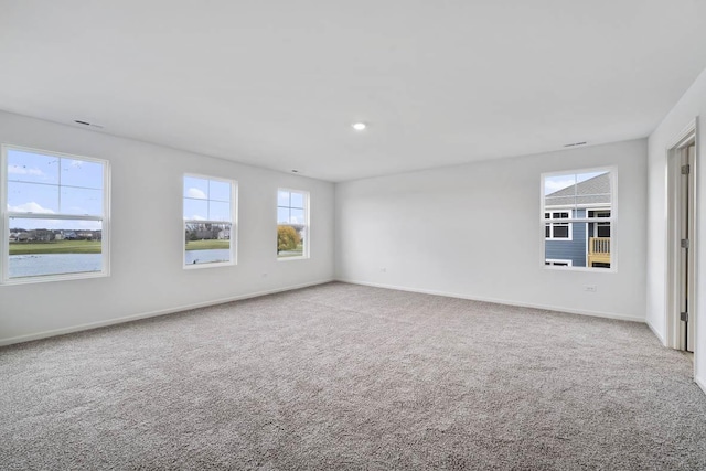 empty room featuring a water view and carpet floors