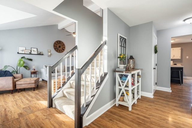 stairs with hardwood / wood-style floors, lofted ceiling with beams, and ceiling fan