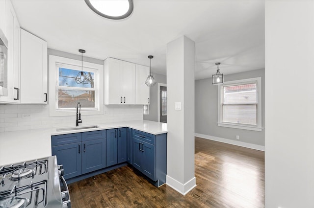 kitchen with blue cabinets, gas stove, sink, and white cabinets