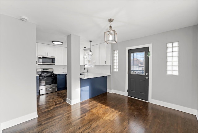 kitchen with sink, stainless steel appliances, decorative backsplash, white cabinets, and decorative light fixtures